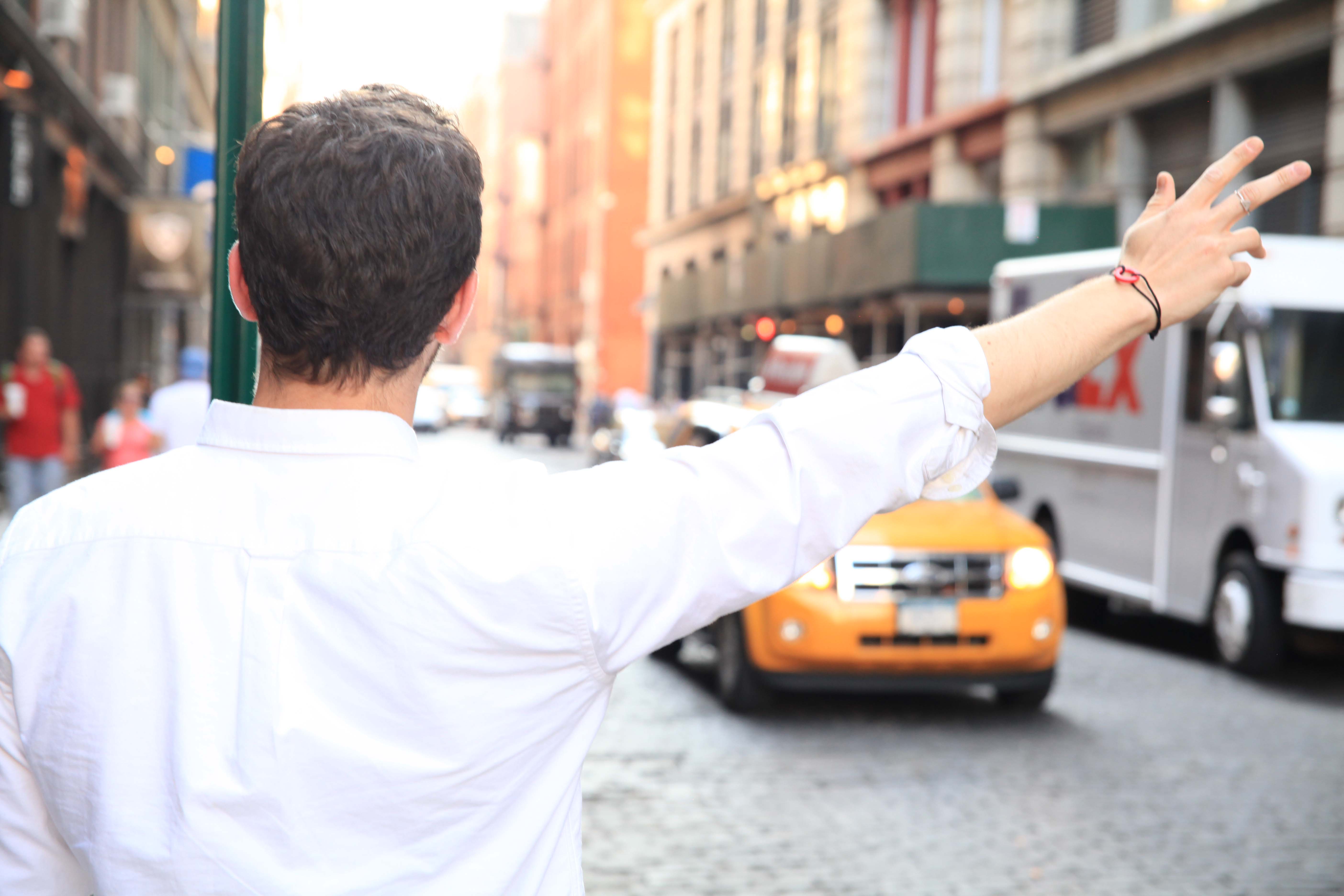 Man hailing taxi cab wearing Comcast Cares Day bracelet